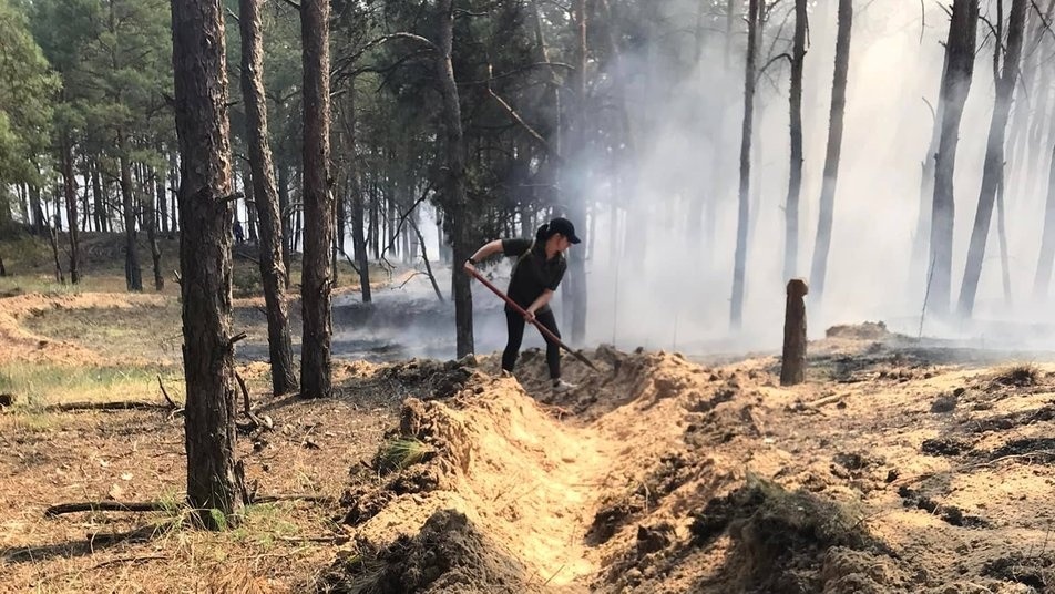 Жінка гасить пожежу в лісі