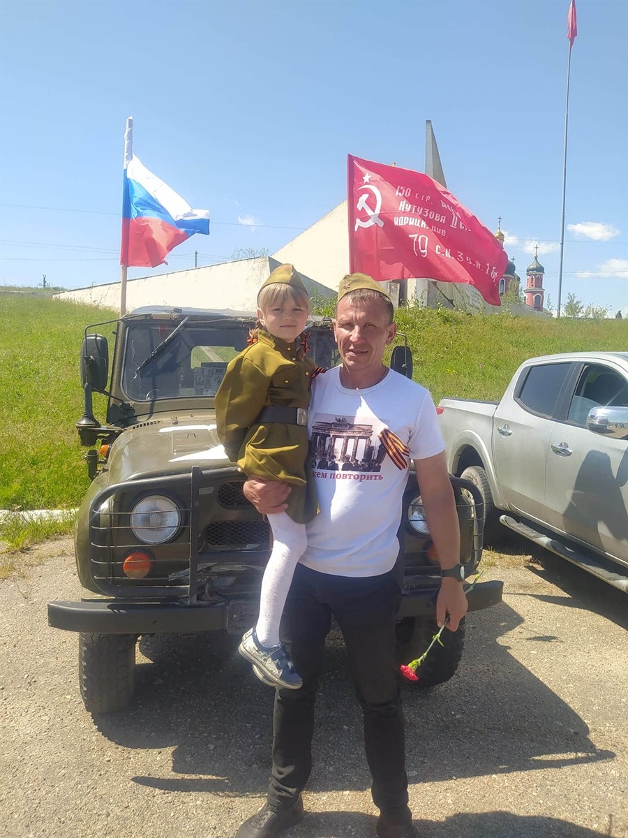 Колаборант Геннадій Малюков демонструє радянський та російський прапори